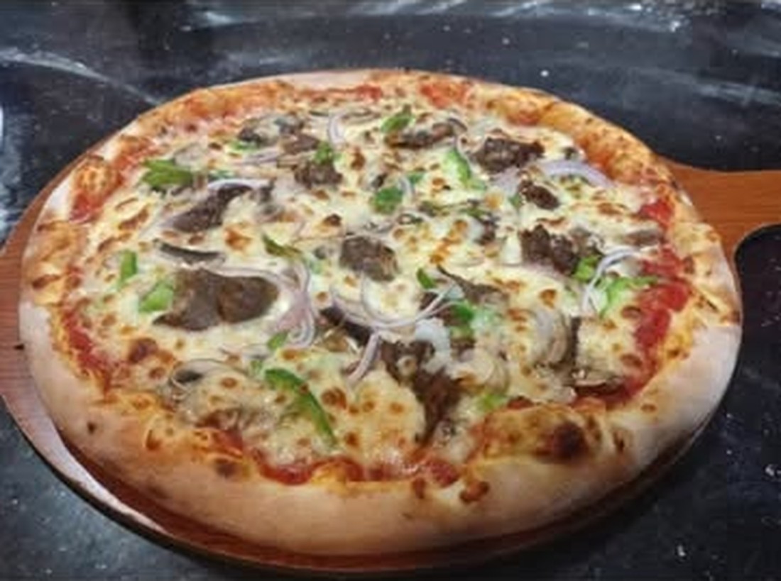 Fornello steak pizza on a wooden peel